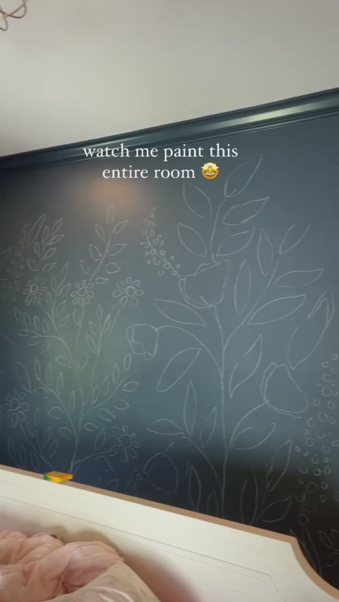 This may contain: a woman is painting a wall with flowers and leaves on the mural in her home