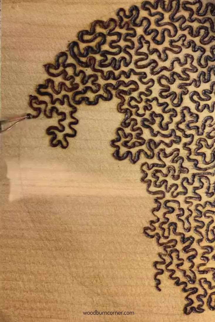 This may contain: a person is using a pair of scissors to cut out the pattern on a piece of wood