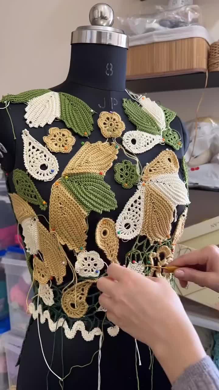 This may contain: a woman is working on a dress with crochet