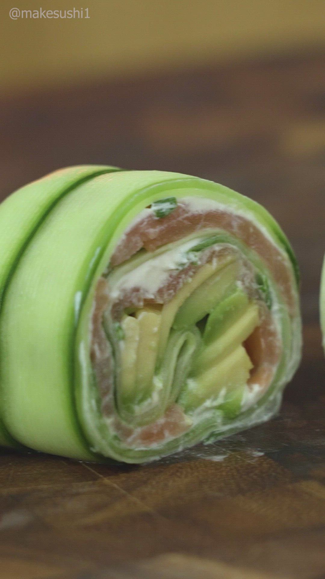 This may contain: an apple and cucumber roll cut in half on a wooden table with one section open