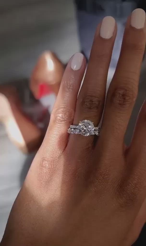 This may contain: a woman's hand with a diamond ring on top of her finger and the other hand holding an engagement ring