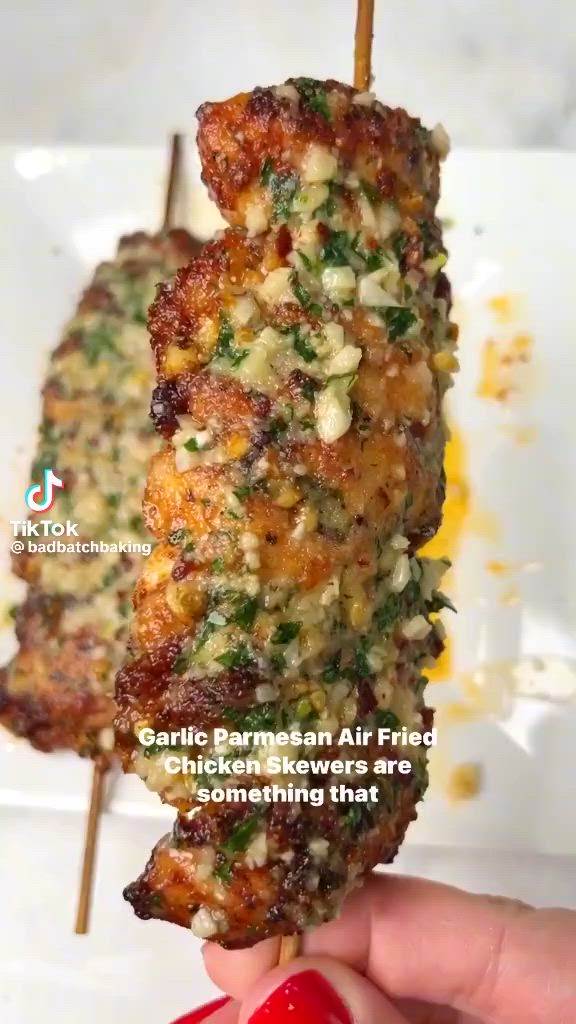 This may contain: someone is holding up some food on a skewer with the words garlic parmesan air fried chicken and something that looks like something that