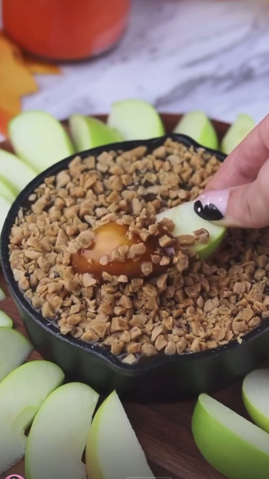 This may contain: a person is dipping an apple into some granola