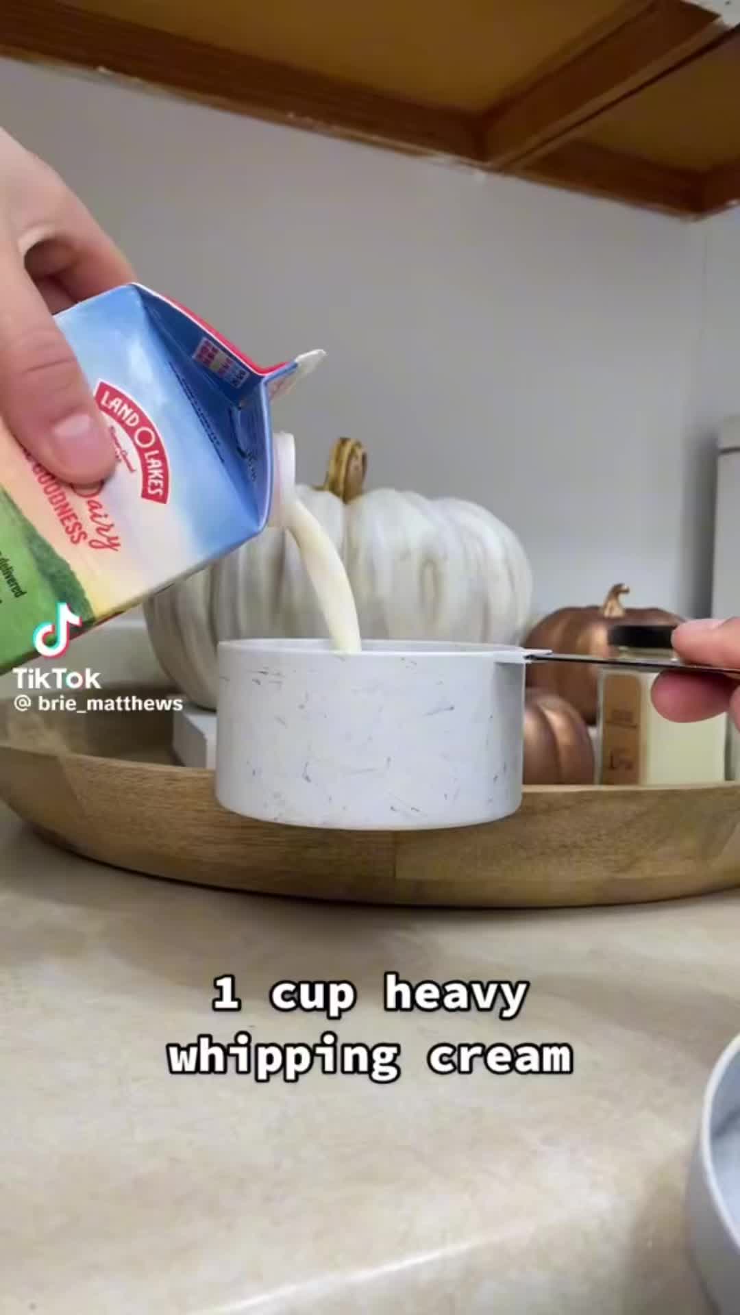 This may contain: someone pouring cream into a cup on top of a counter