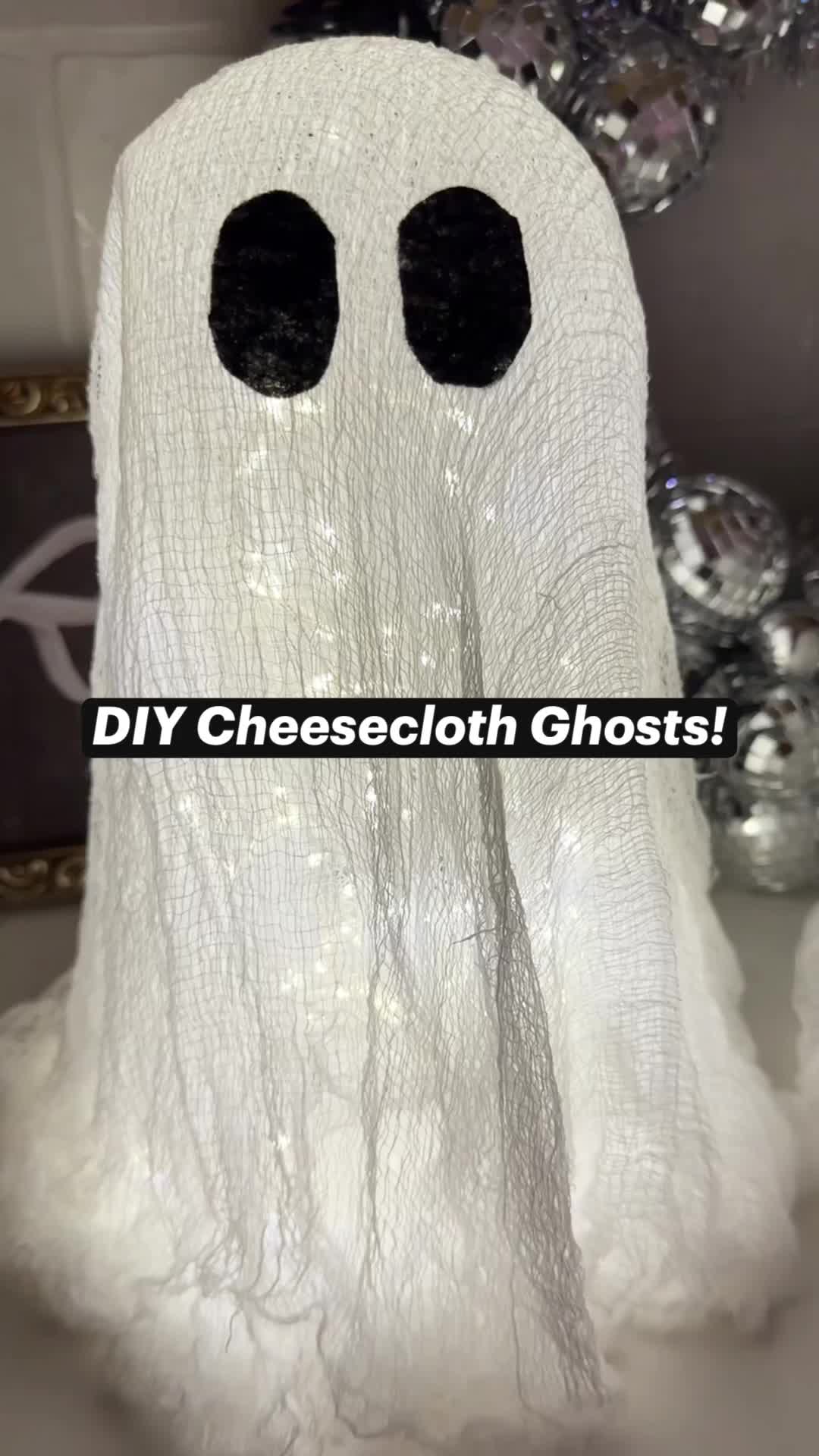 This may contain: a white ghost with black eyes is sitting in front of a christmas tree and has the words diy cheesecloth ghost