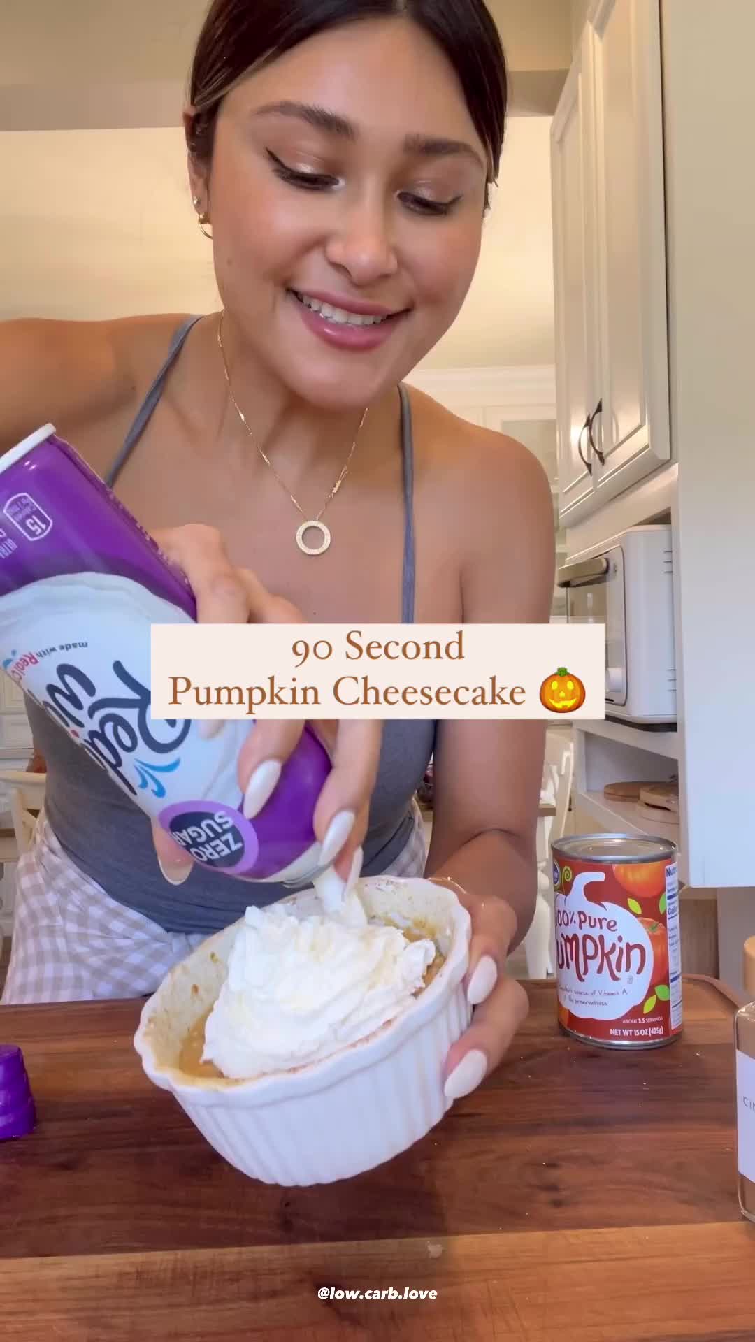 This may contain: a woman is pouring pumpkin cheesecake into a small bowl with whipped cream on top