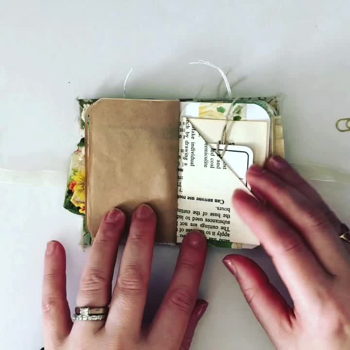 This may contain: two hands are working on an altered book