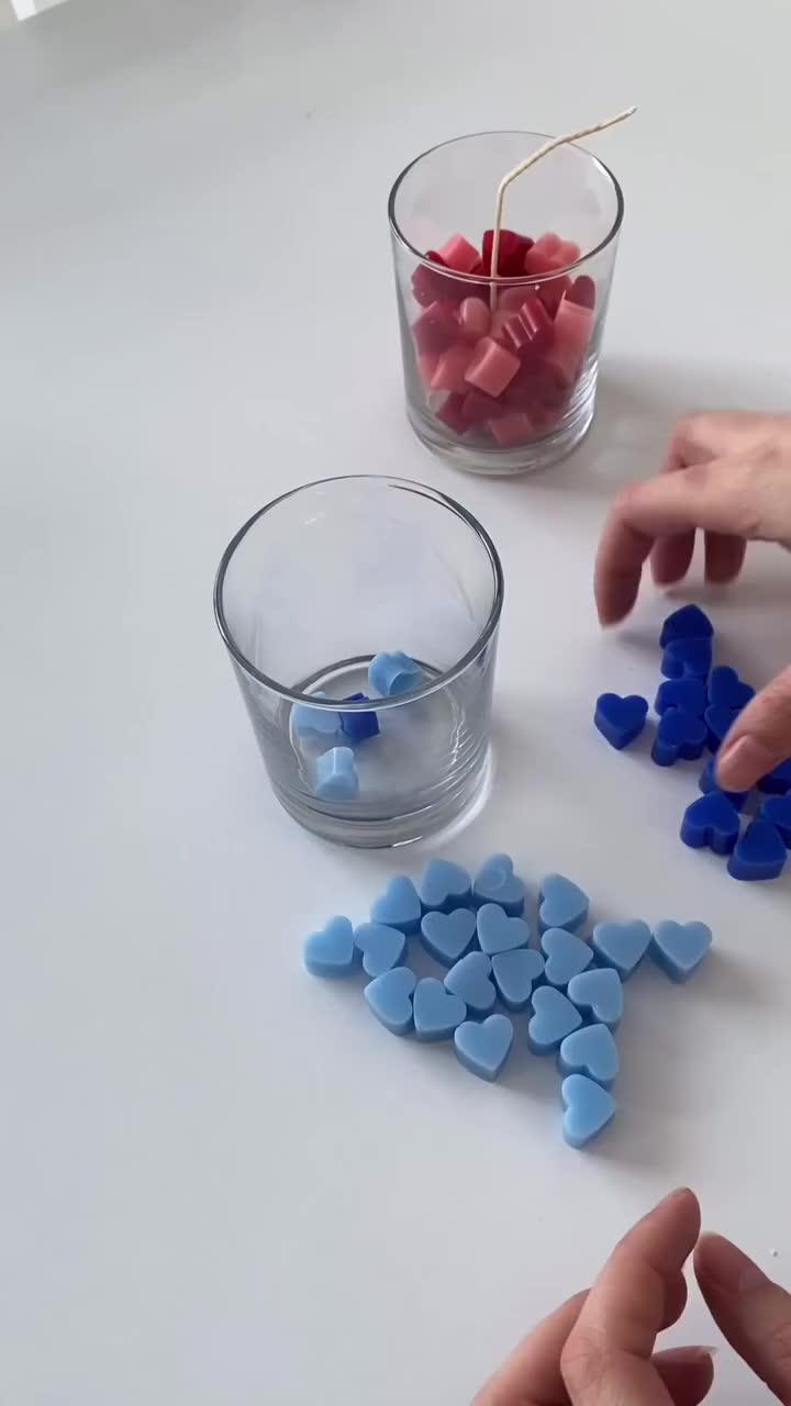 This may contain: two people holding candles with red, white and blue cubes in them