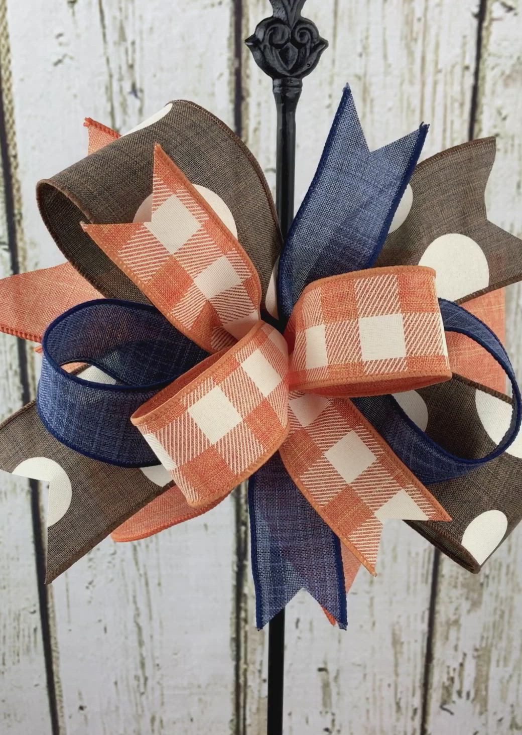 This may contain: an orange, white and blue bow on top of a metal stand with wood planks in the background