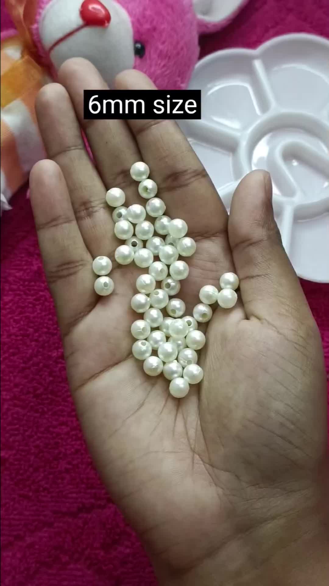 This may contain: a person is holding some white pearls in their hand and there are other items on the table