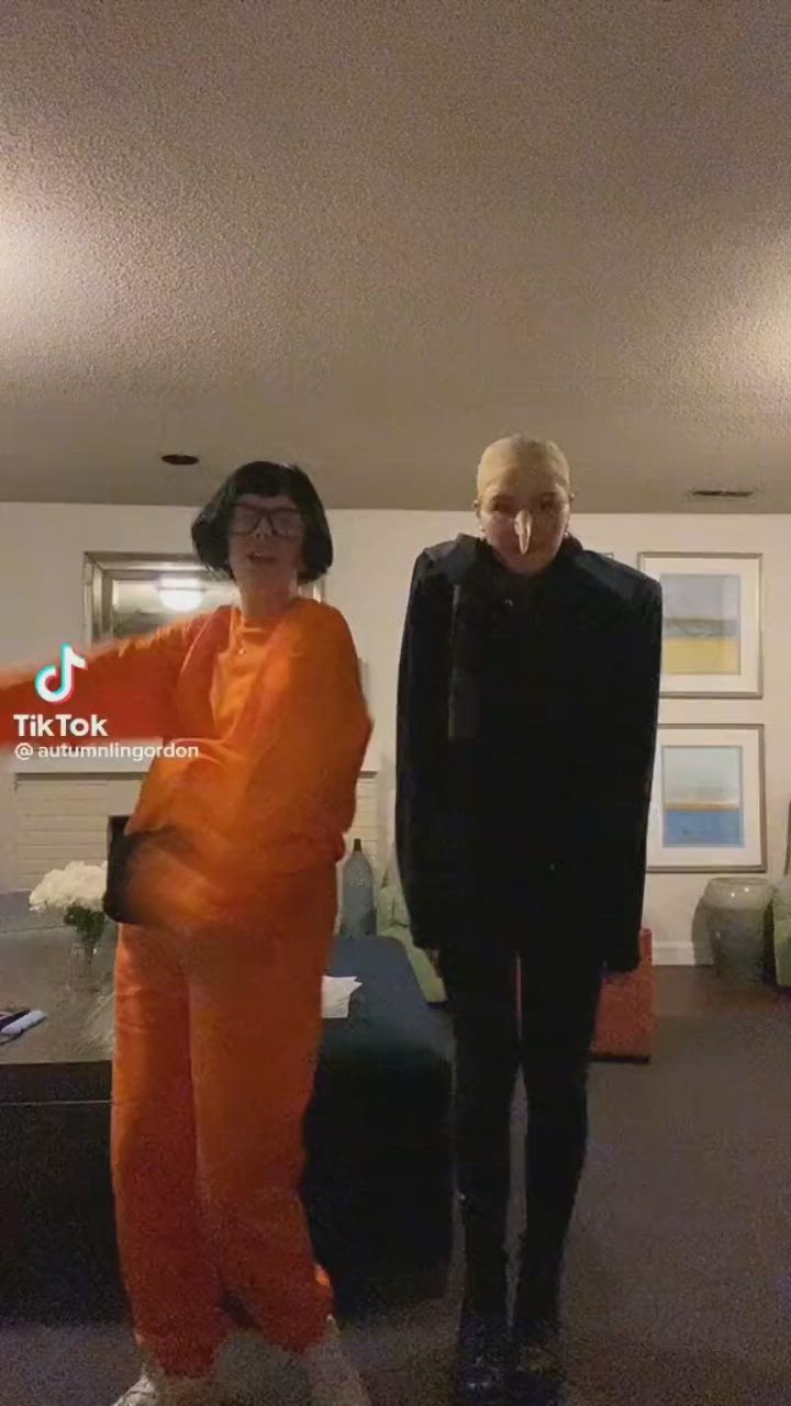 This may contain: two women in orange and black outfits standing next to each other on a carpeted floor