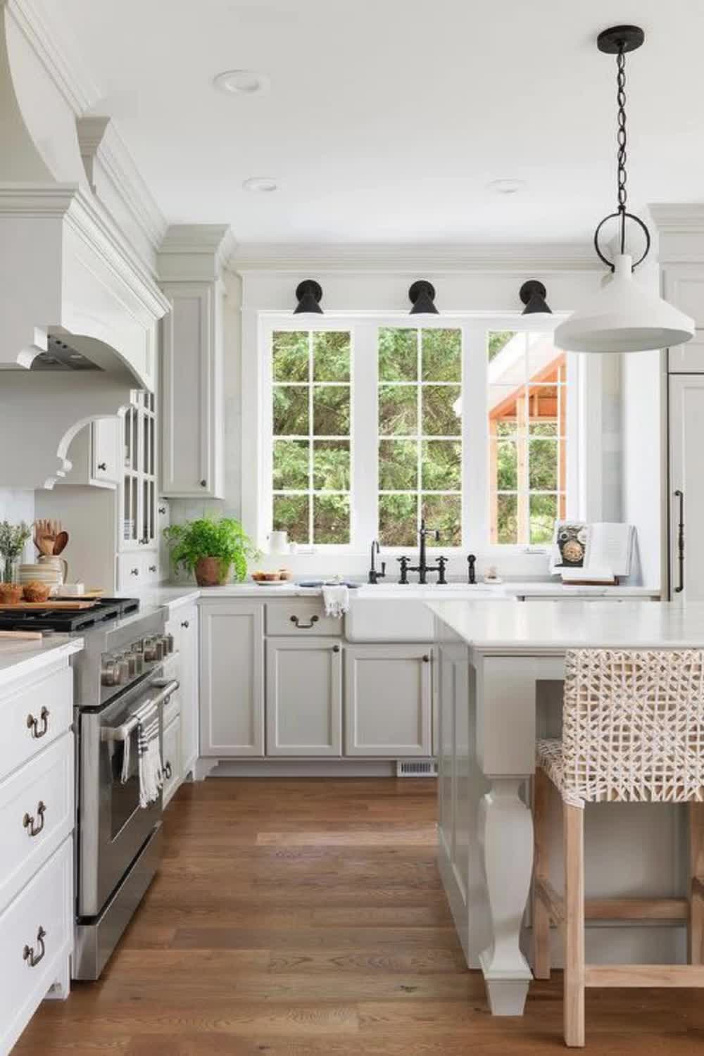 This may contain: a kitchen with white cabinets and wooden floors