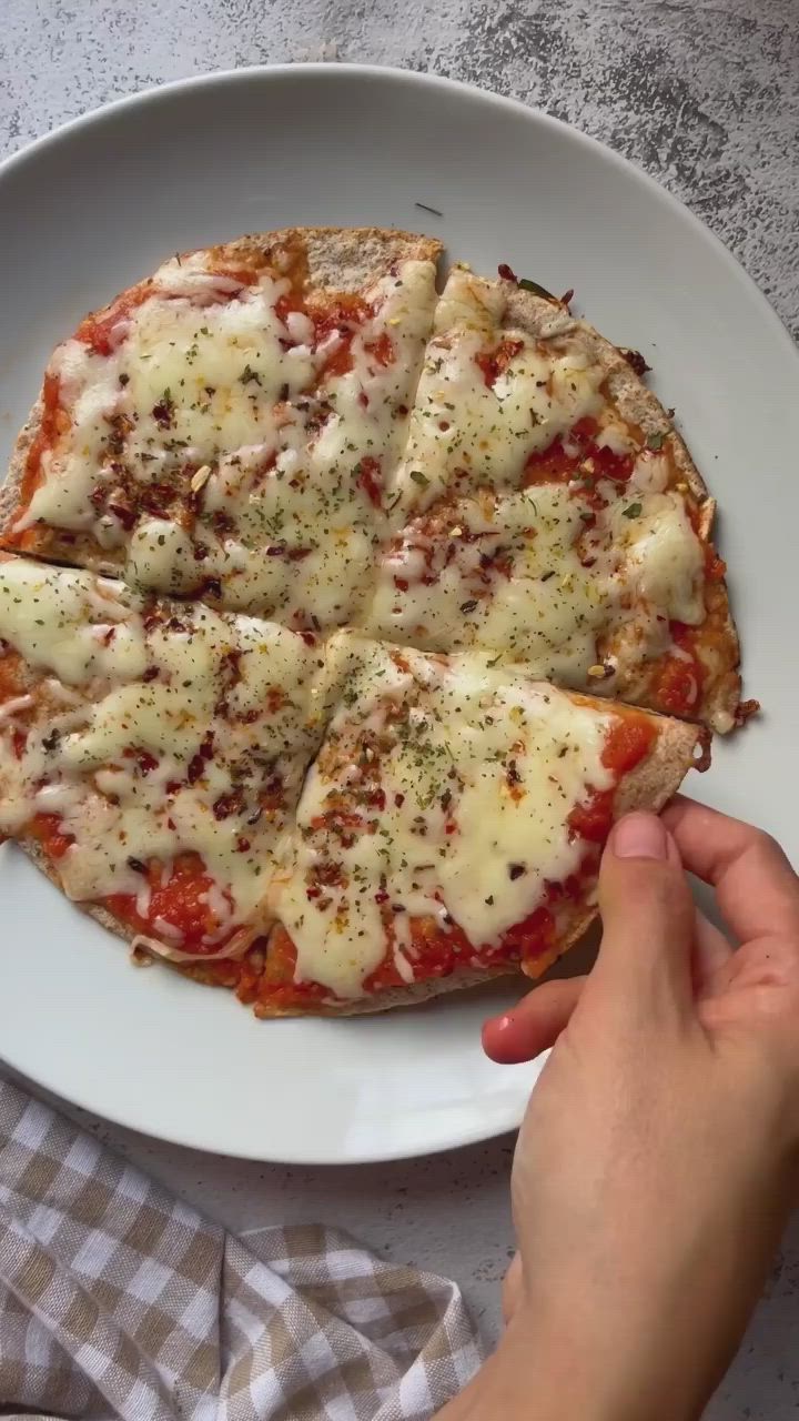 This may contain: a person is holding a piece of pizza on a plate with the word faquipizza