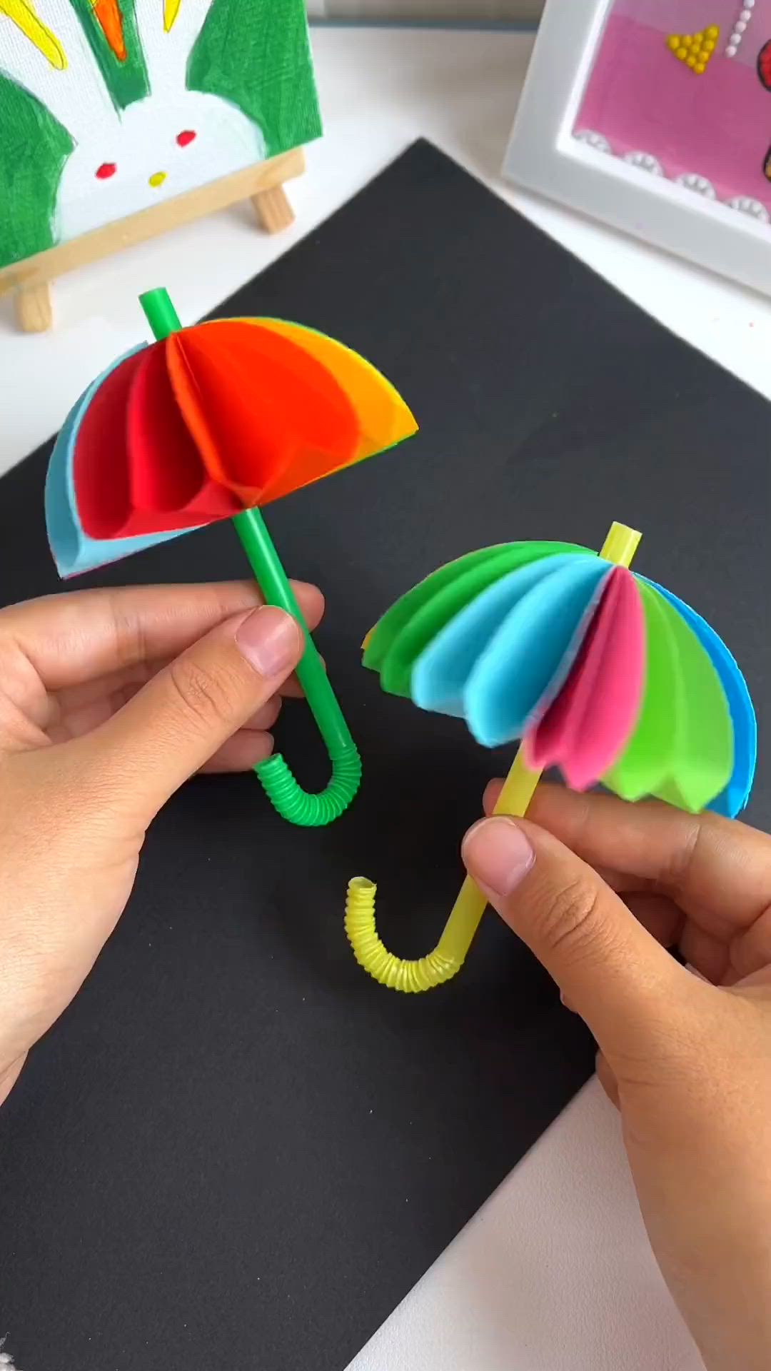 This may contain: two colorful umbrellas are being held up by someone's hand on a table