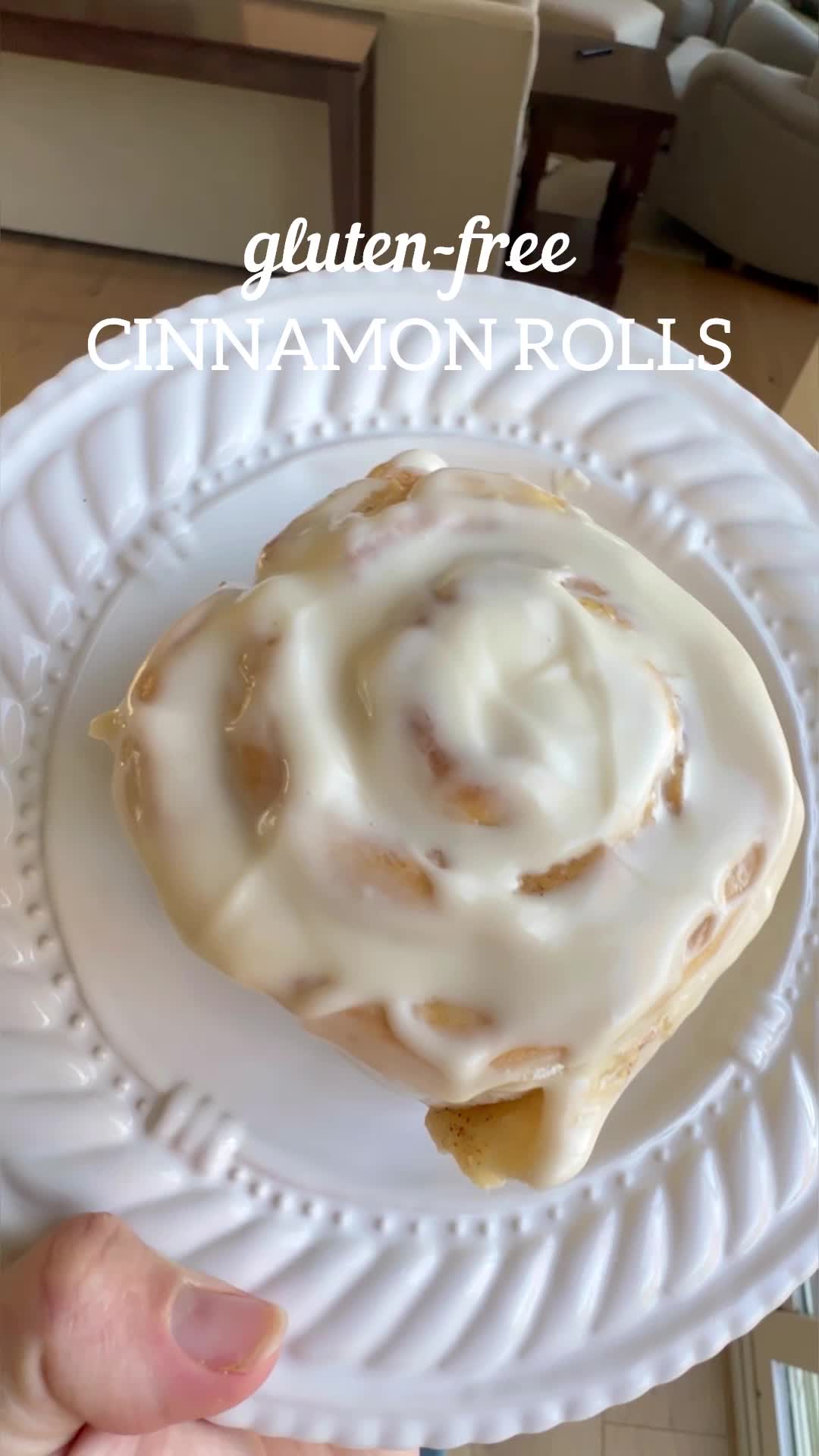 This may contain: a person holding a white plate with a cinnamon roll on it and the text gluten - free cinnamon rolls