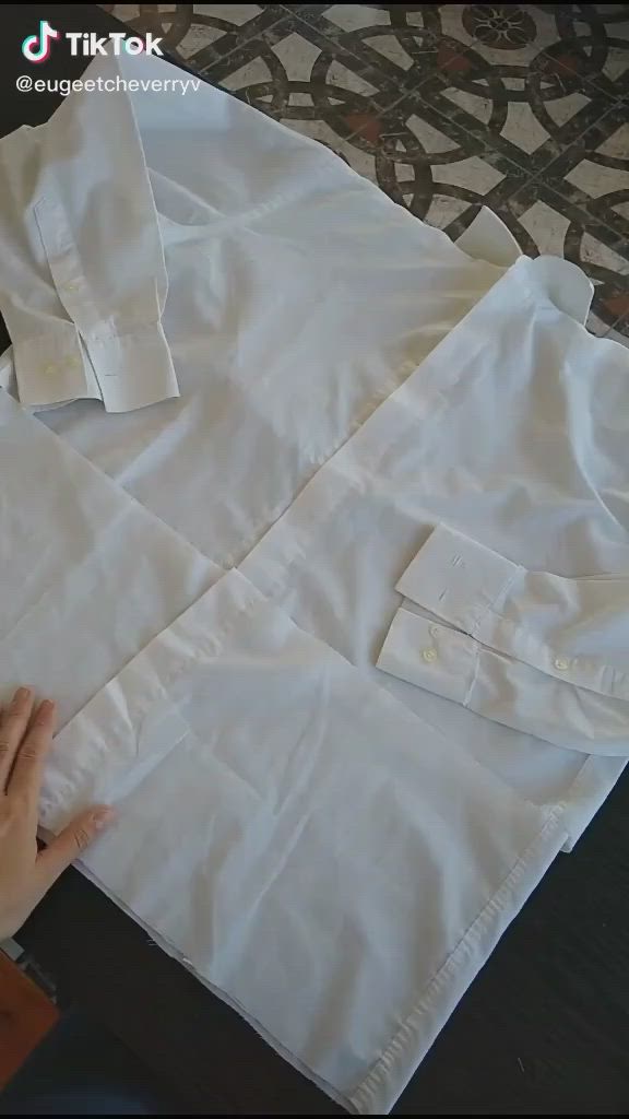 This may contain: someone is making a shirt out of white linens on the floor with their hands