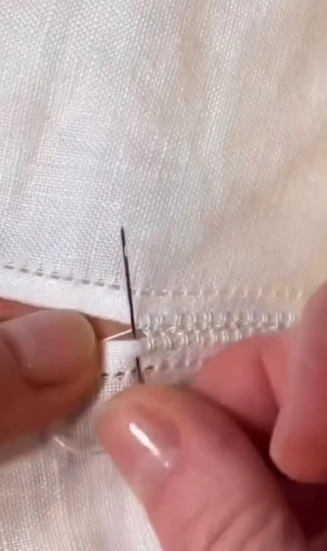 This may contain: someone is stitching the side of a white piece of fabric with a pair of scissors