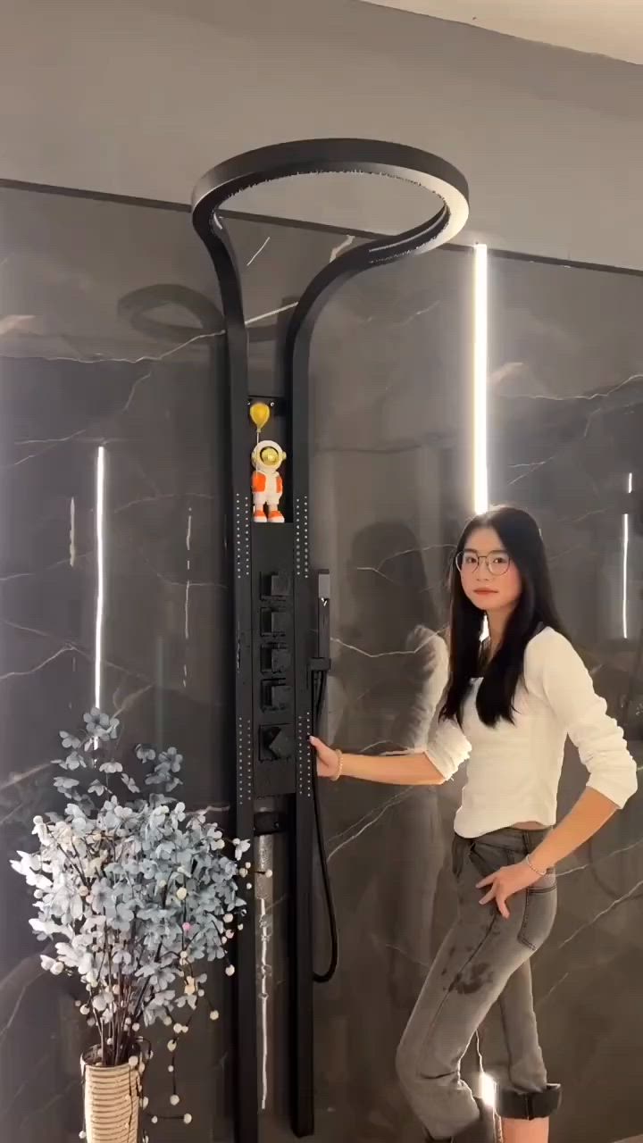 This may contain: a woman standing in front of a shower with a hose attached to it's side