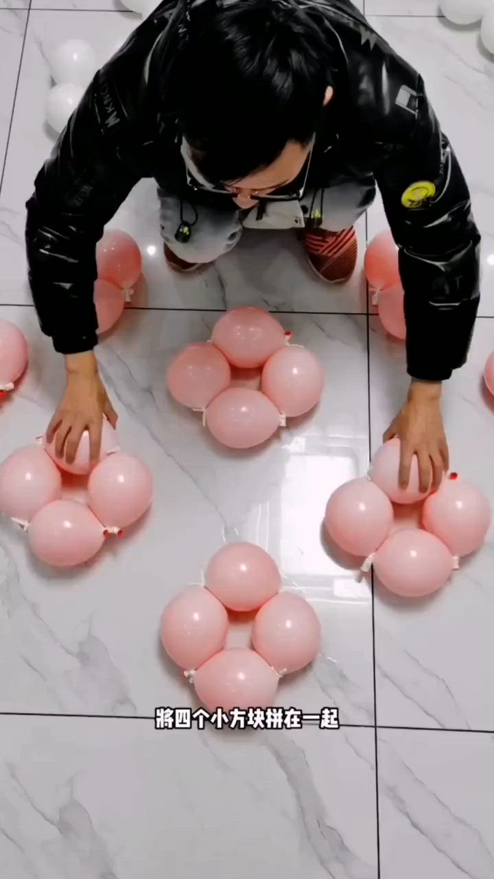 This may contain: a man standing on top of a white floor surrounded by pink balloon balls in front of him