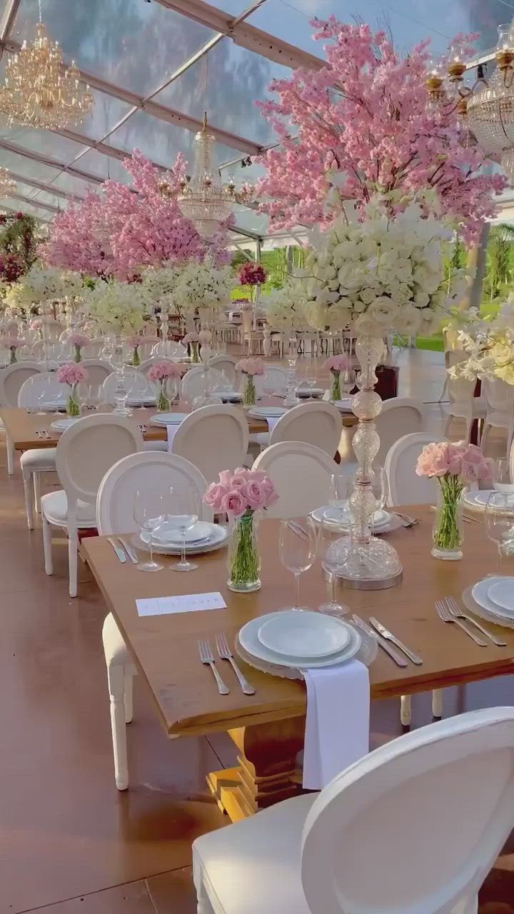 This may contain: the tables are set with white chairs and pink flowers in vases on each table