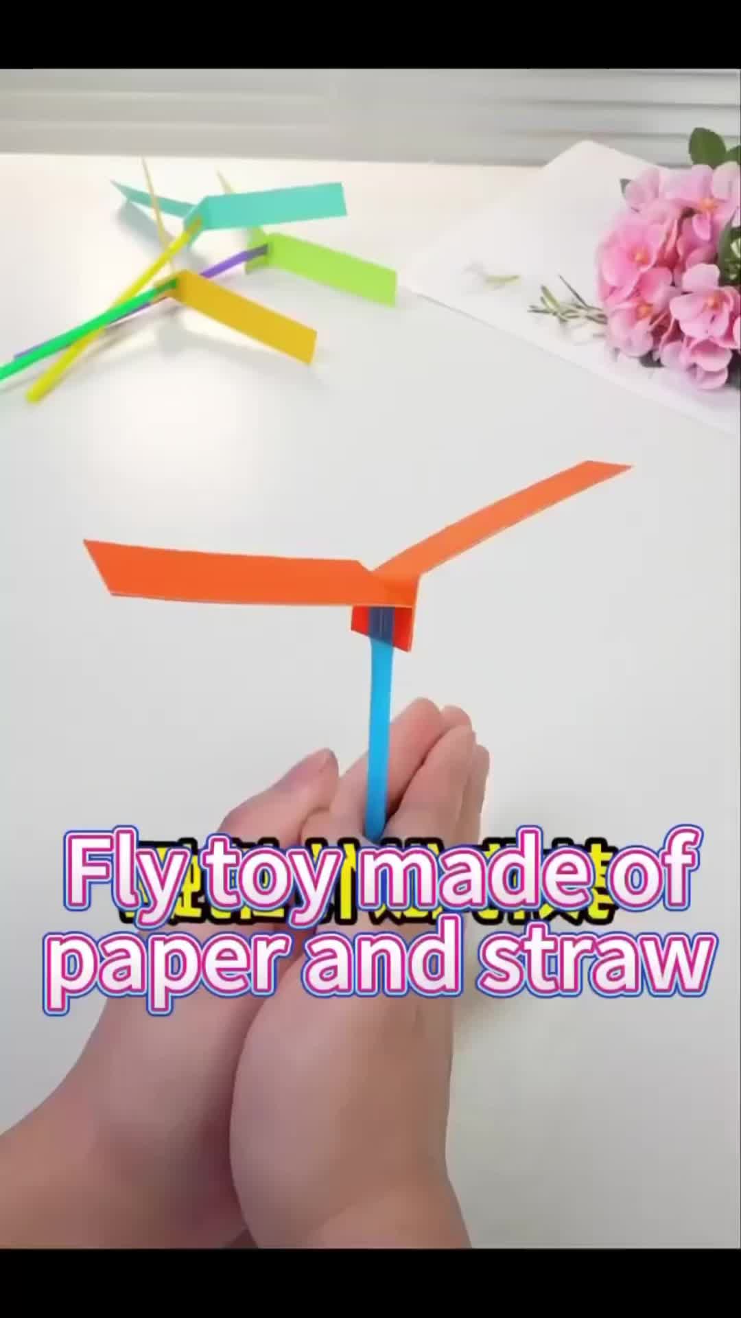 This may contain: someone is making a paper and straw airplane