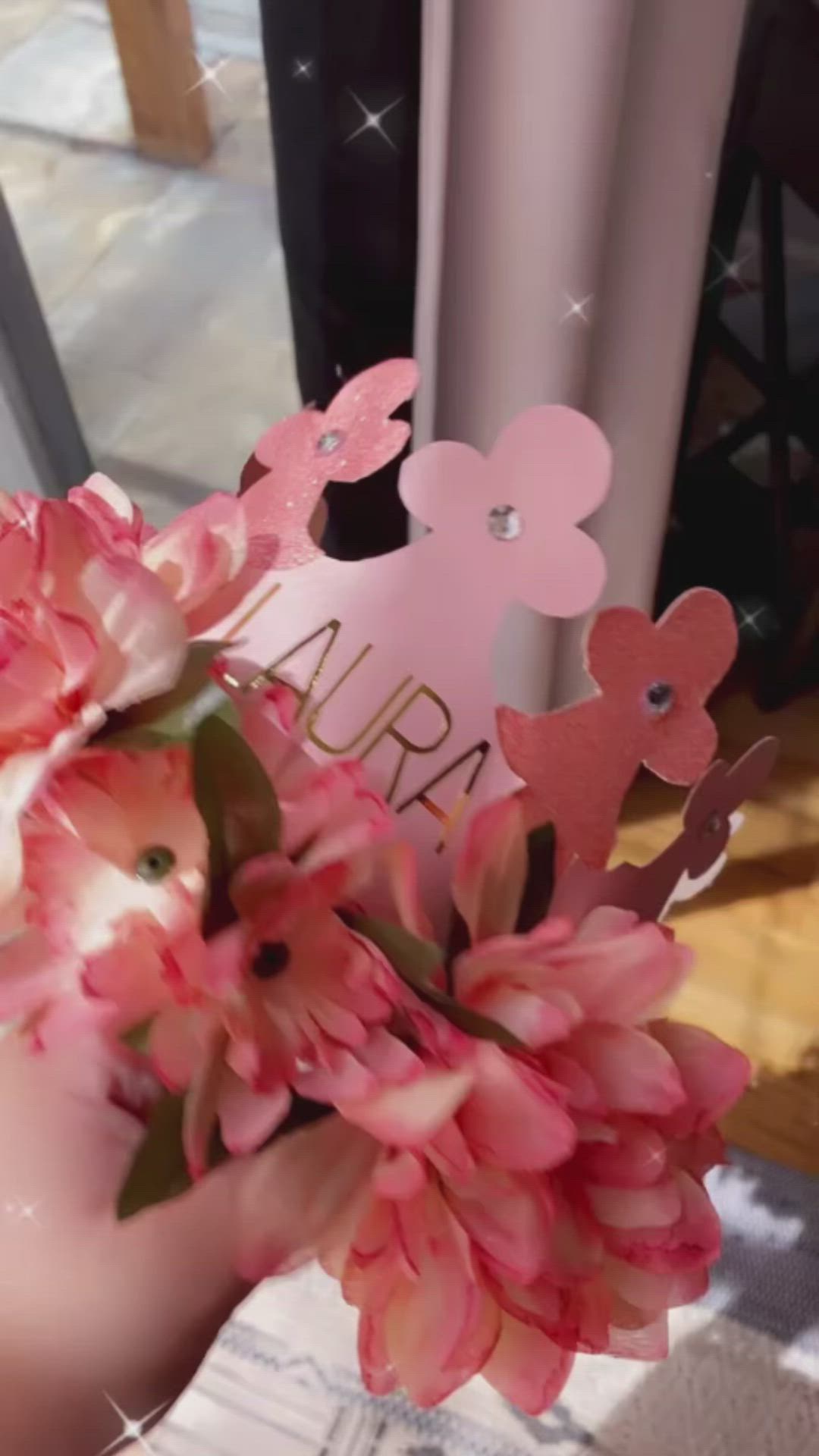 This may contain: a person holding pink flowers in front of a window with the word aria on it