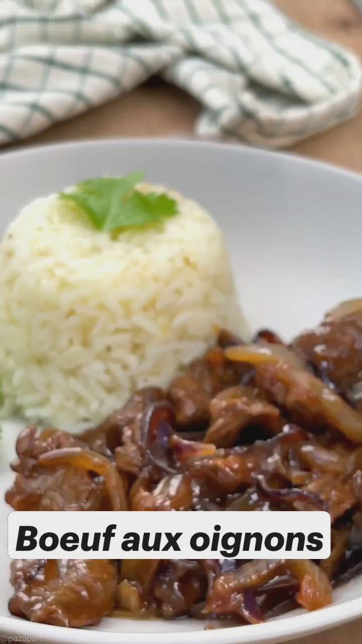 This may contain: a white plate topped with meat and rice next to a green leafy garnish