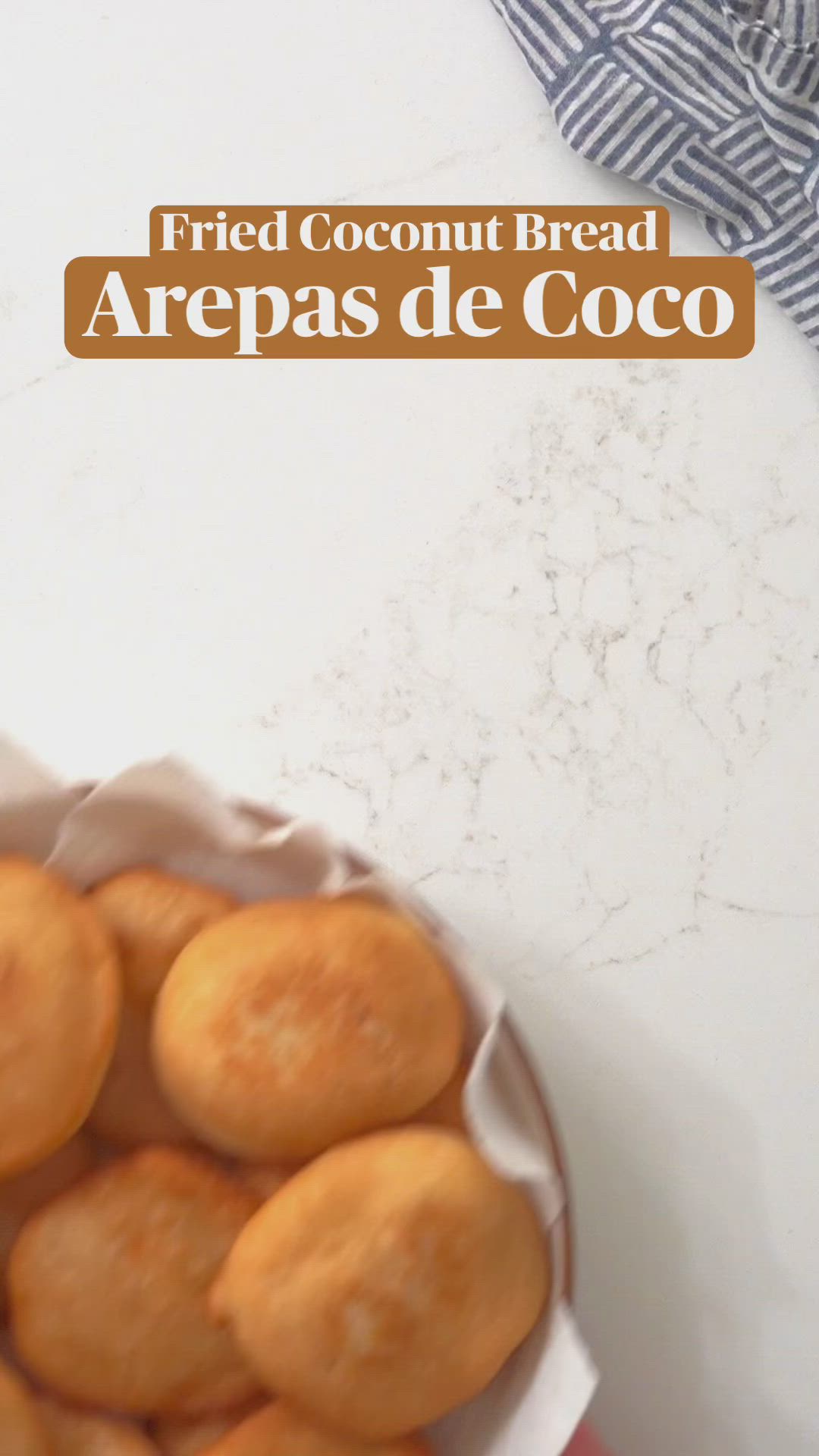 This may contain: two hands holding a fried coconut bread in front of a plate with other food items