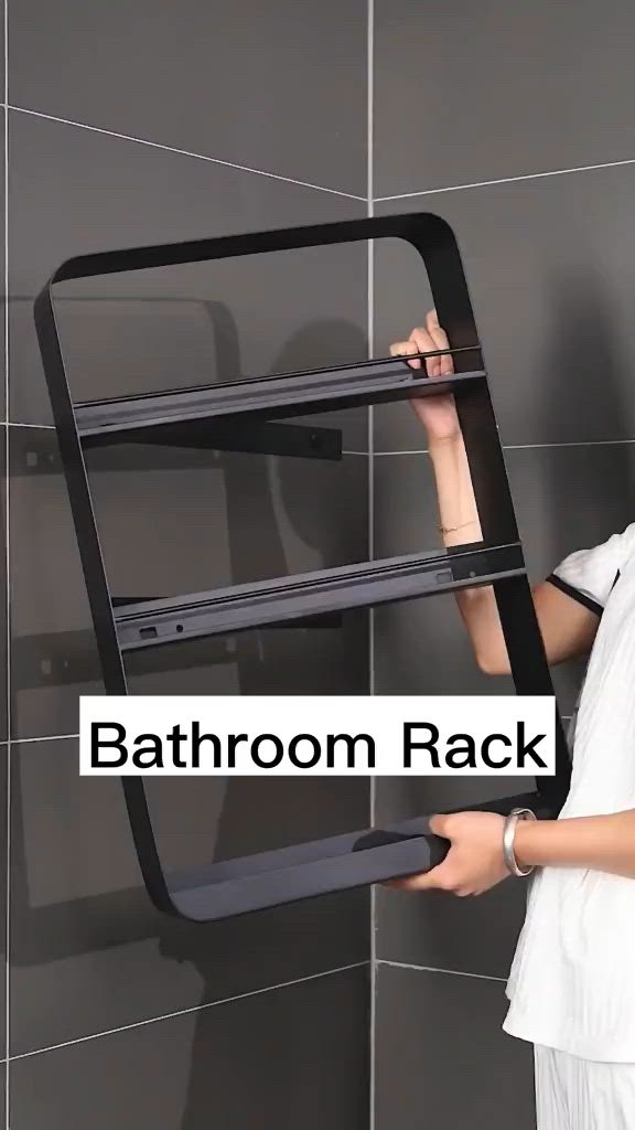 This may contain: a woman in white shirt holding up a black rack with shelves on it and the words bathroom rack above her