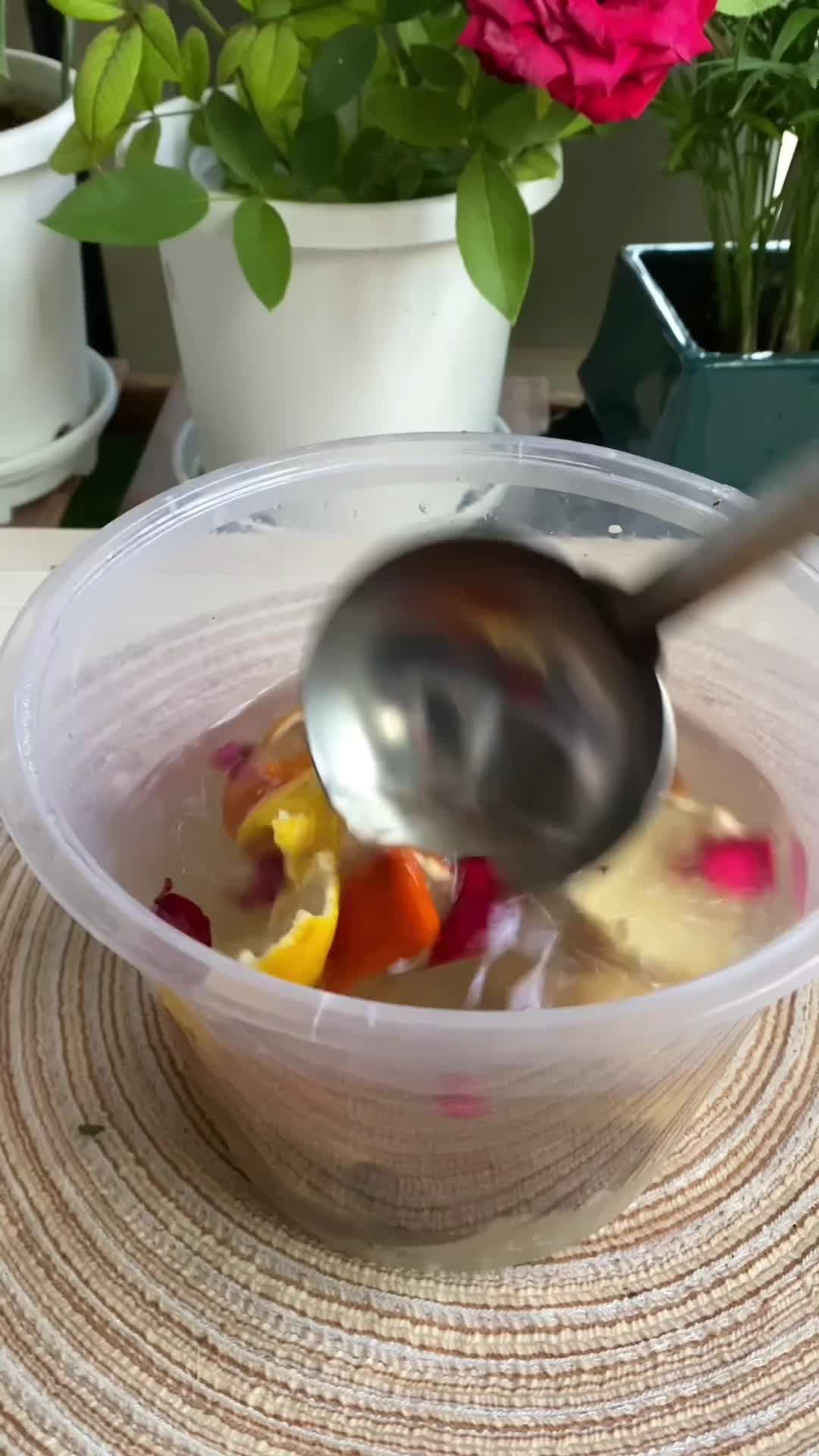 This may contain: a plastic bowl filled with lots of different types of flowers and vegetables next to a potted plant