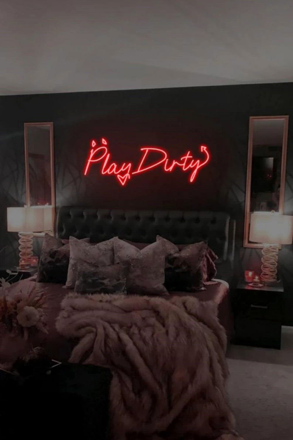 This contains: A bed room with a neatly made bed and a neon sign