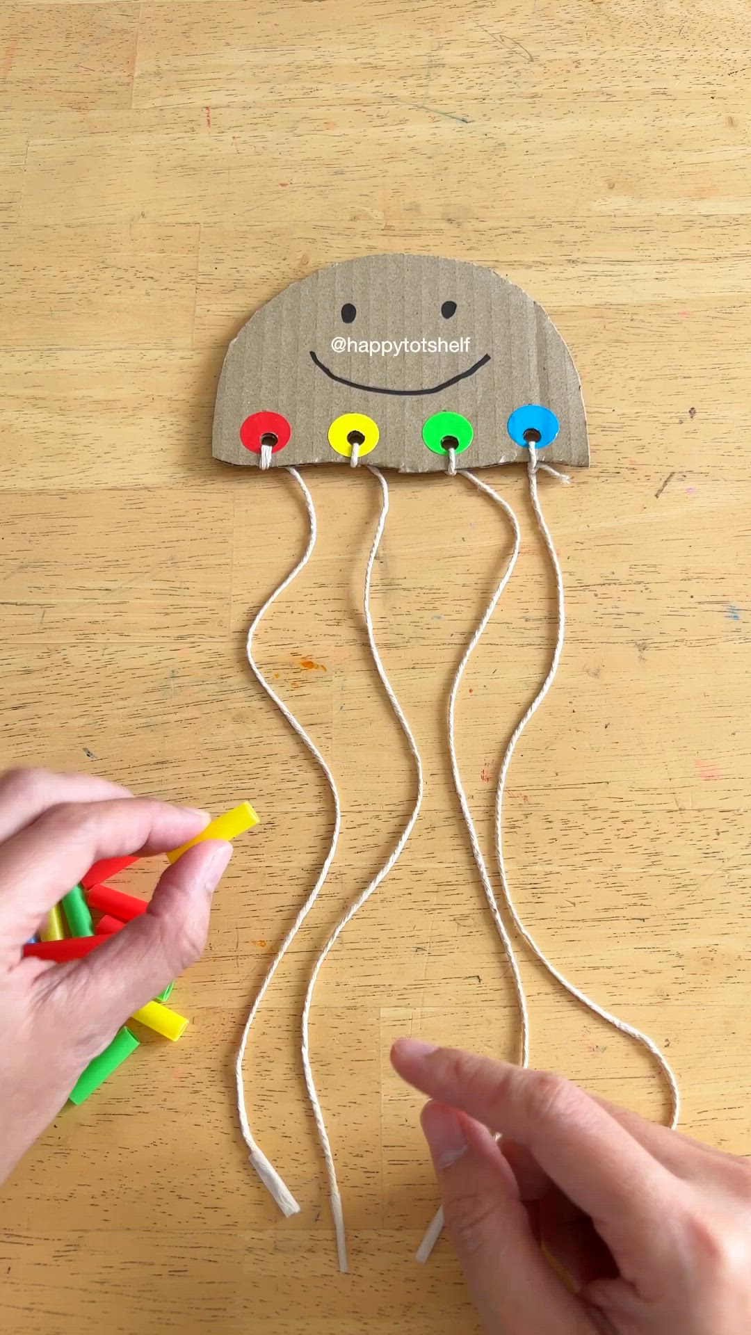 This may contain: someone is holding two toothbrushes in the shape of a jellyfish on a wooden table