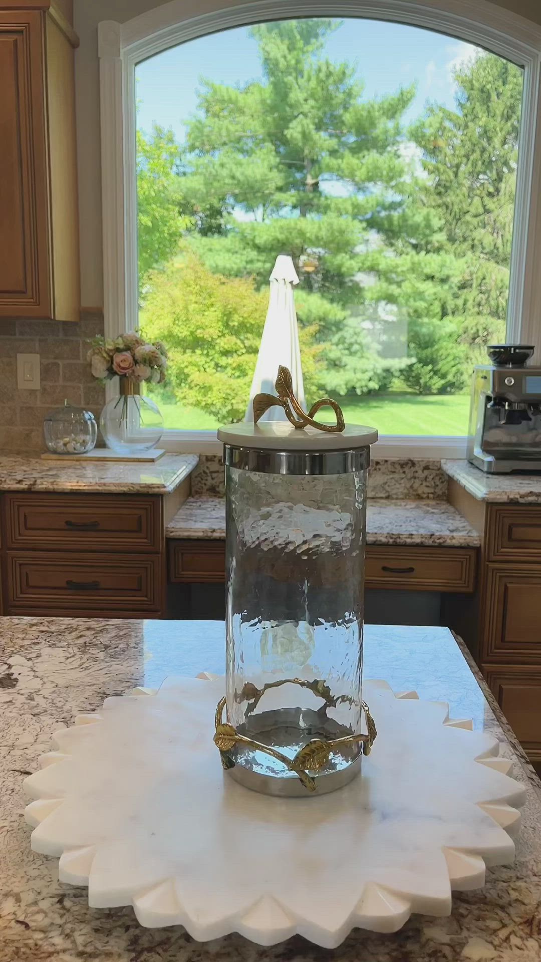 This may contain: a kitchen counter with a glass vase on top of it and a window in the background