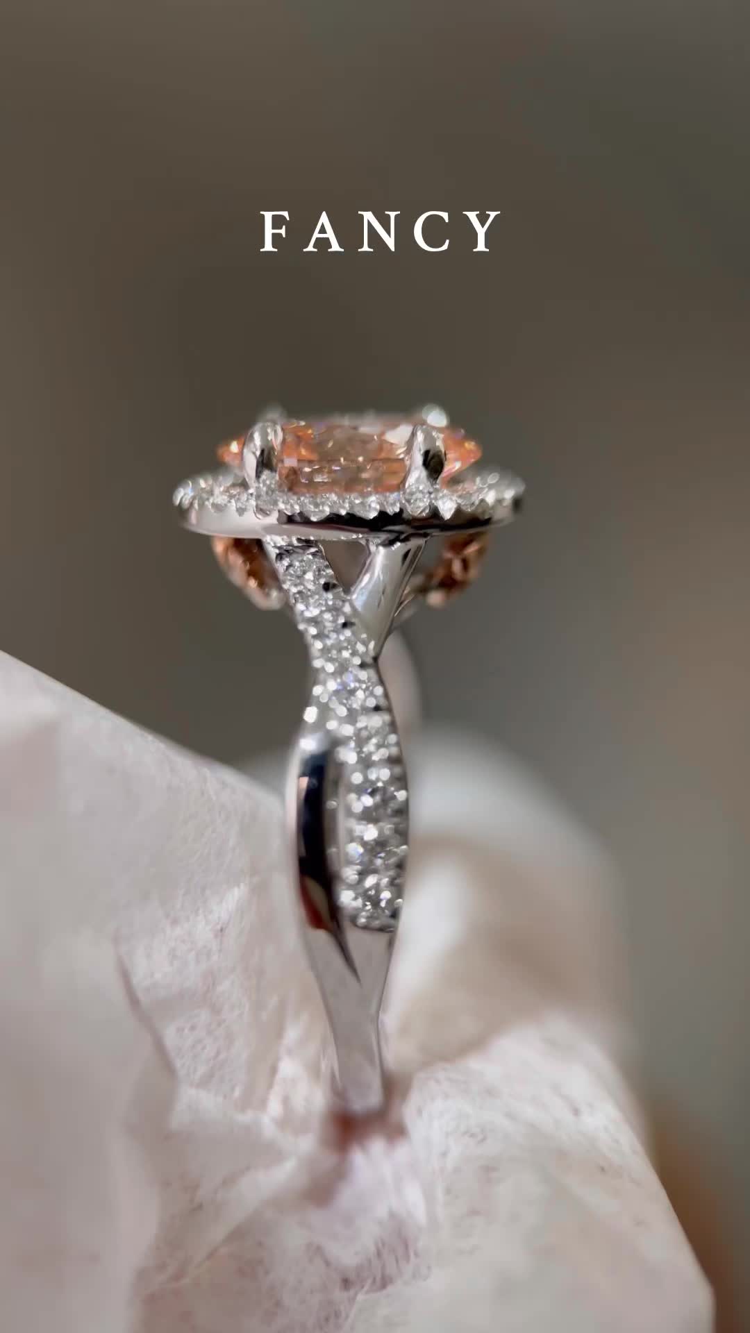 This may contain: an orange diamond ring sitting on top of a white napkin with the words fancy in it