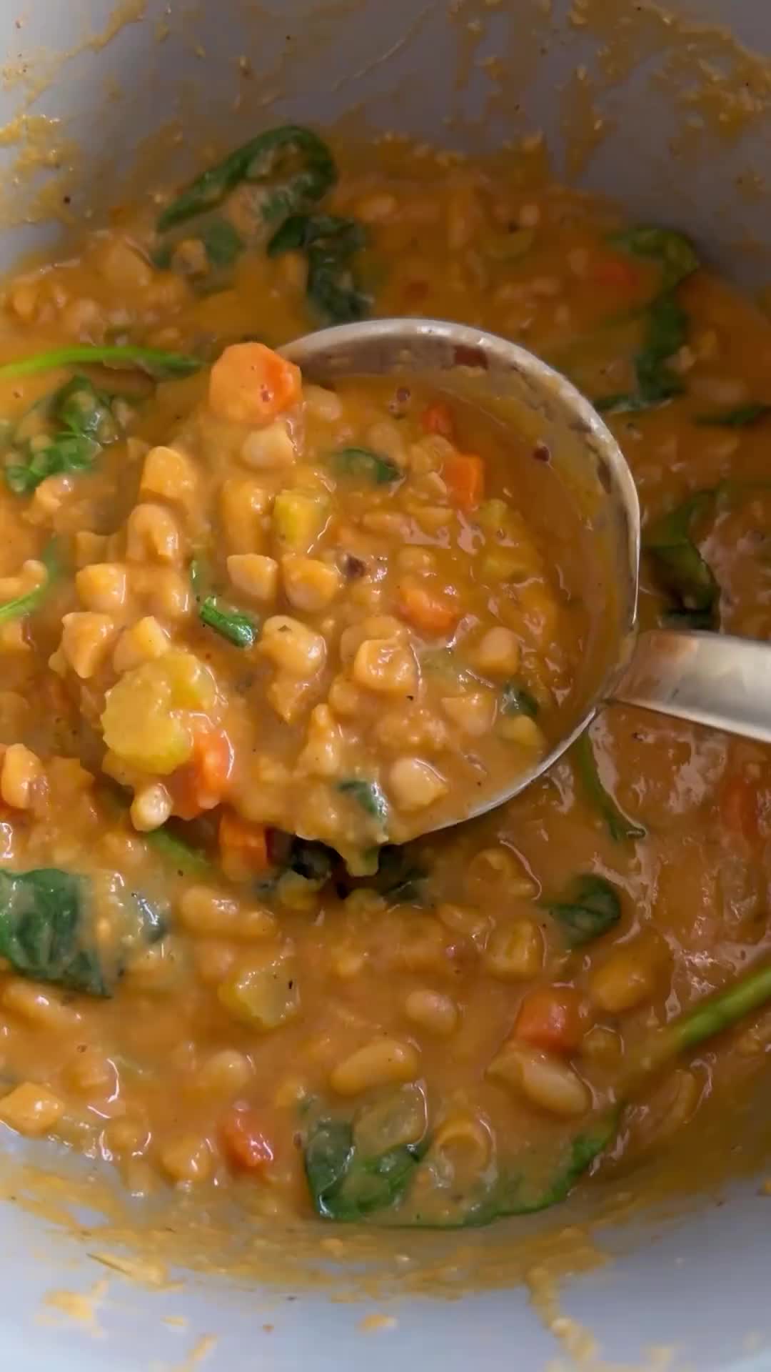 This may contain: a white bowl filled with soup and vegetables