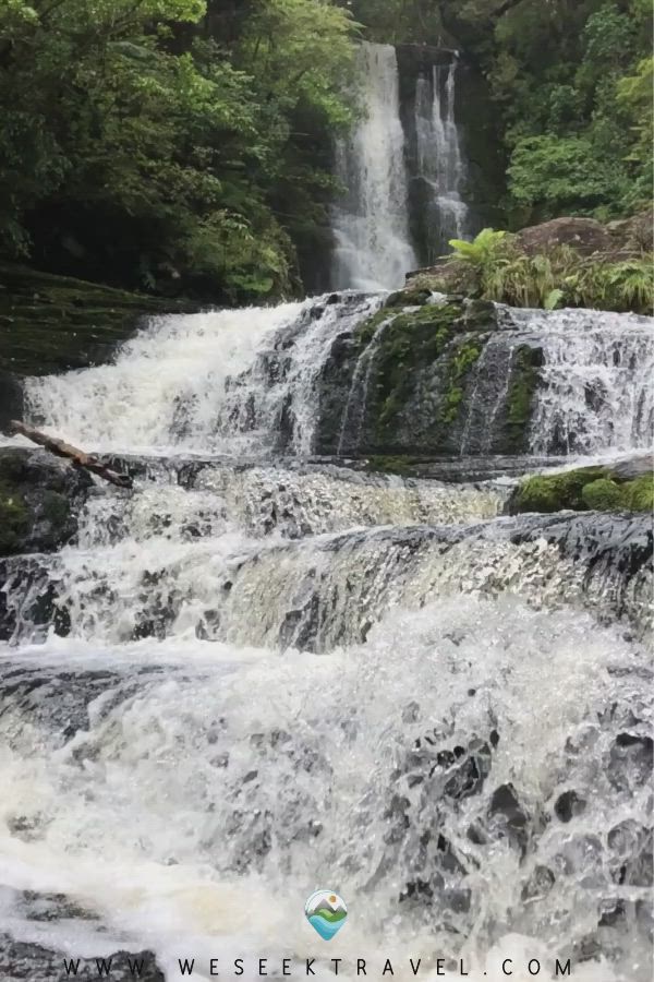 This may contain: a waterfall in the middle of a forest with lots of water flowing down it's sides