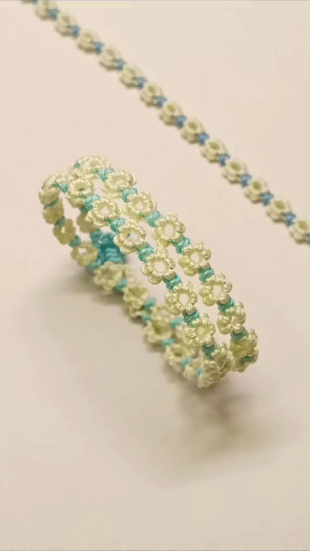 This may contain: a beaded bracelet is shown on a white surface with blue and green beads around it