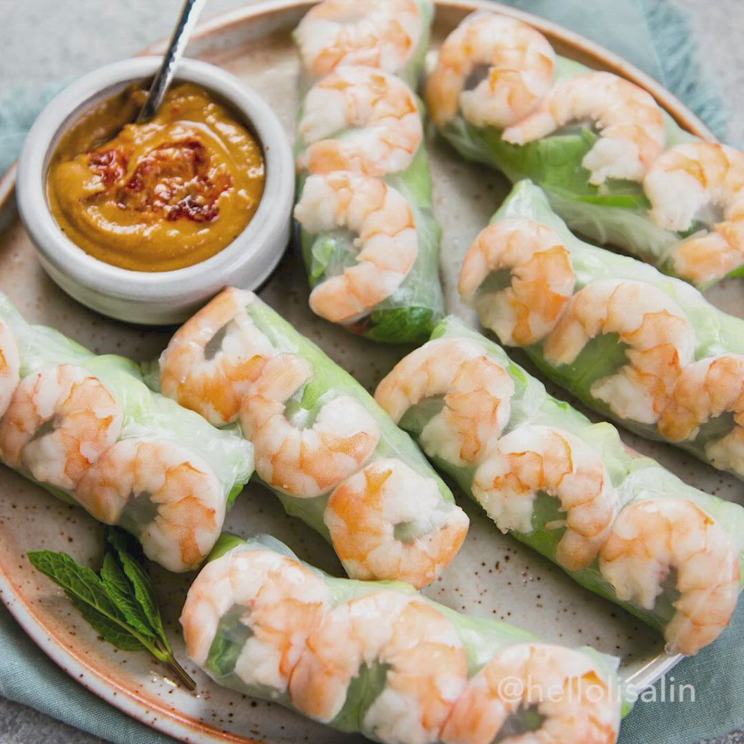 This may contain: shrimp spring rolls on a plate with dipping sauce