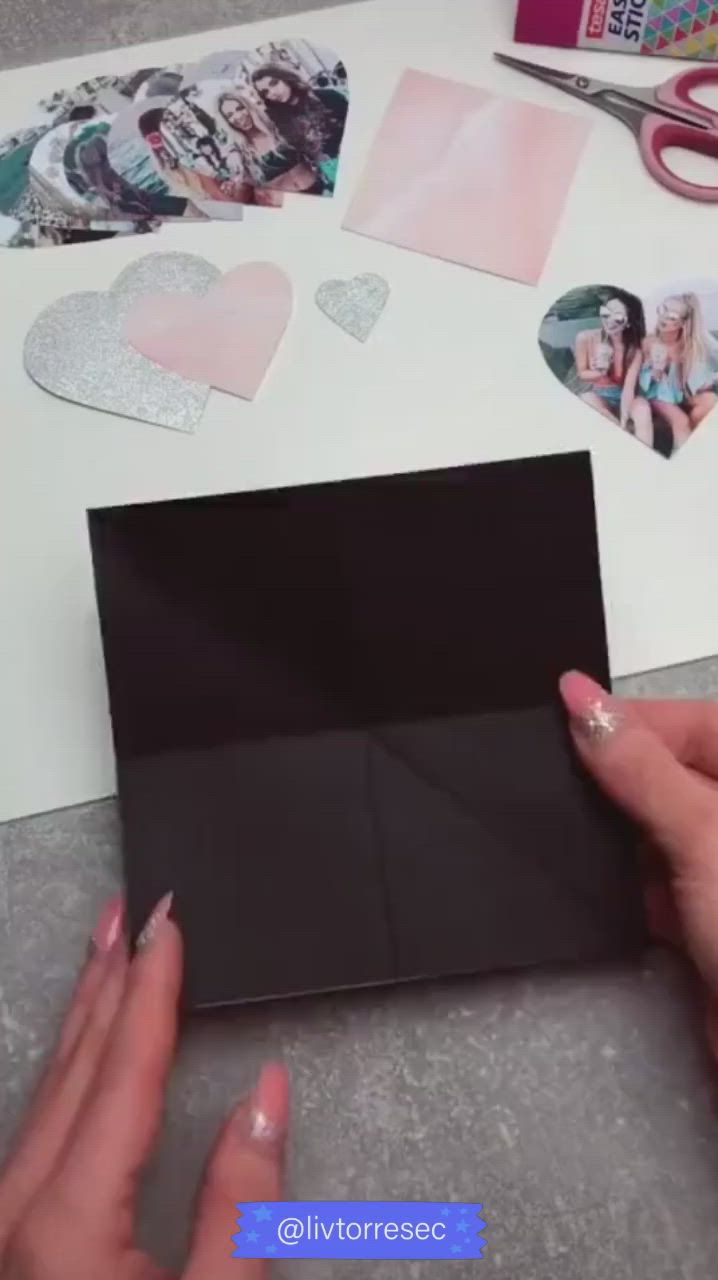 This may contain: someone is cutting out hearts on a piece of black paper with scissors and other crafting supplies