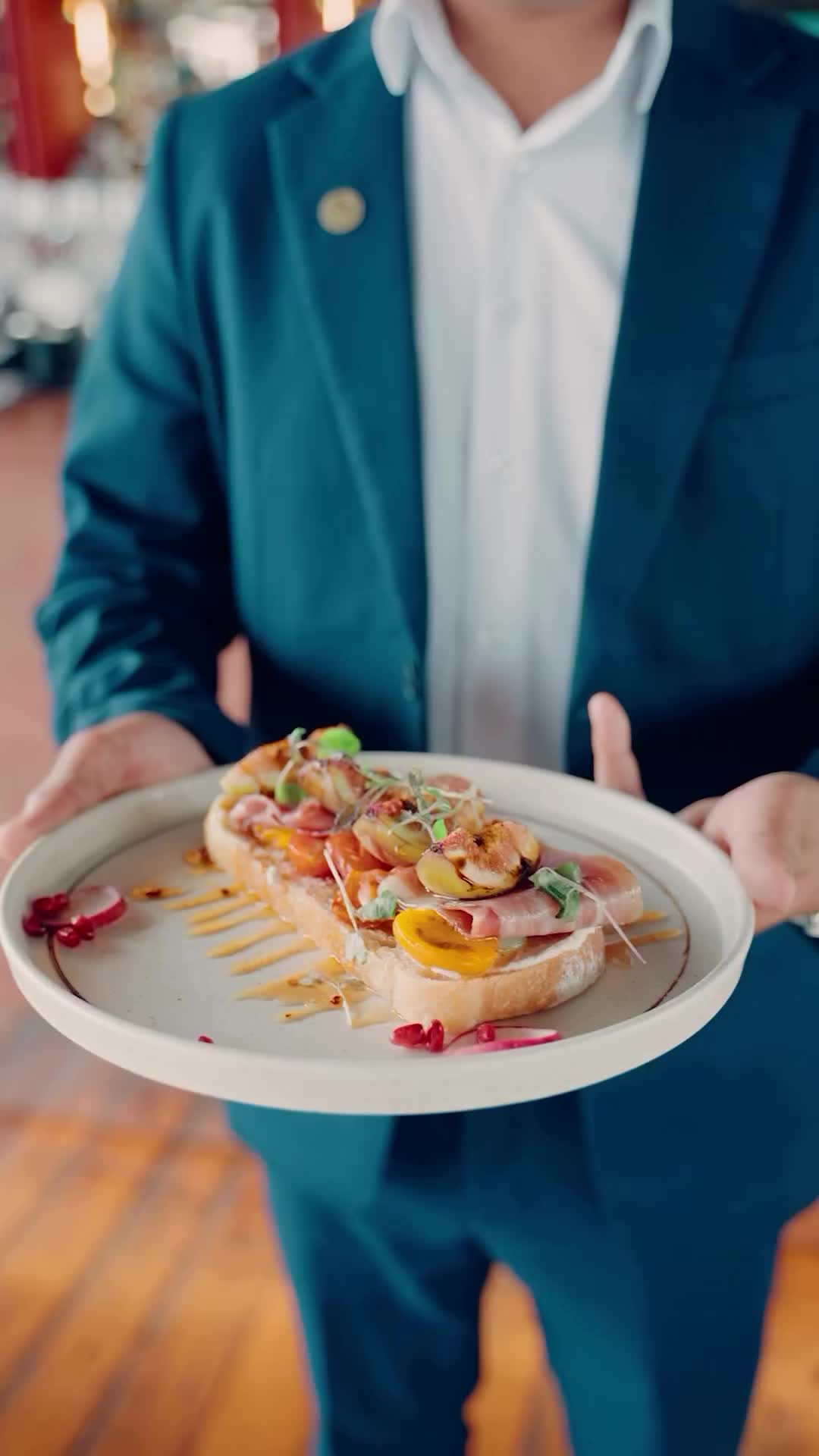 This may contain: a man in a suit holding a plate with food on it