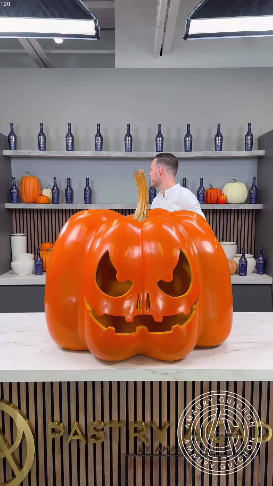 This may contain: a man sitting in front of a giant pumpkin