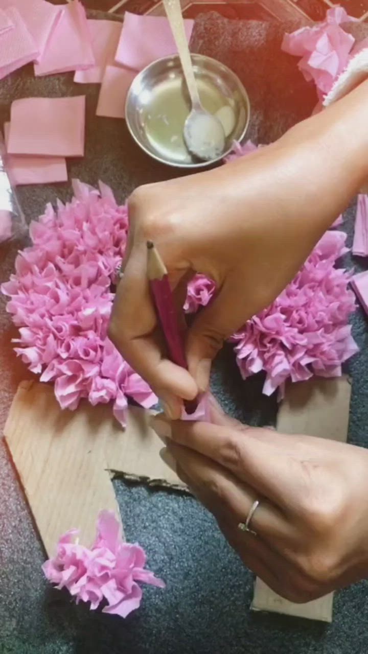 This may contain: someone is making pink flowers out of tissue paper