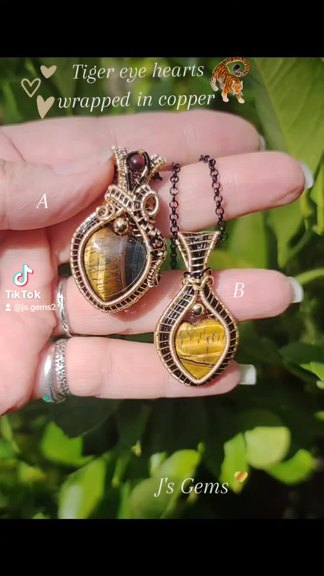 This may contain: a person is holding two necklaces in their hand with the words tiger eye hearts wrapped in copper