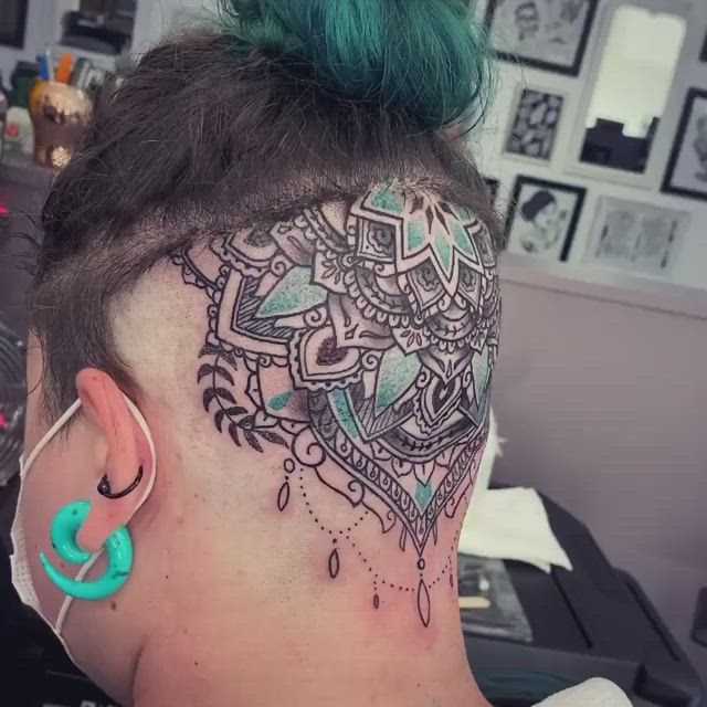 This may contain: a woman with green hair has a tattoo on her head