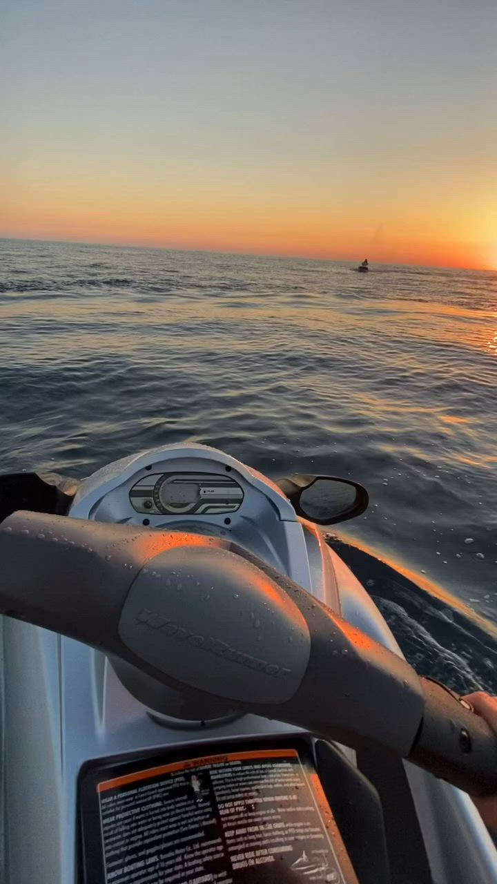 This may contain: the sun is setting over the ocean as seen from a motorboat in the water