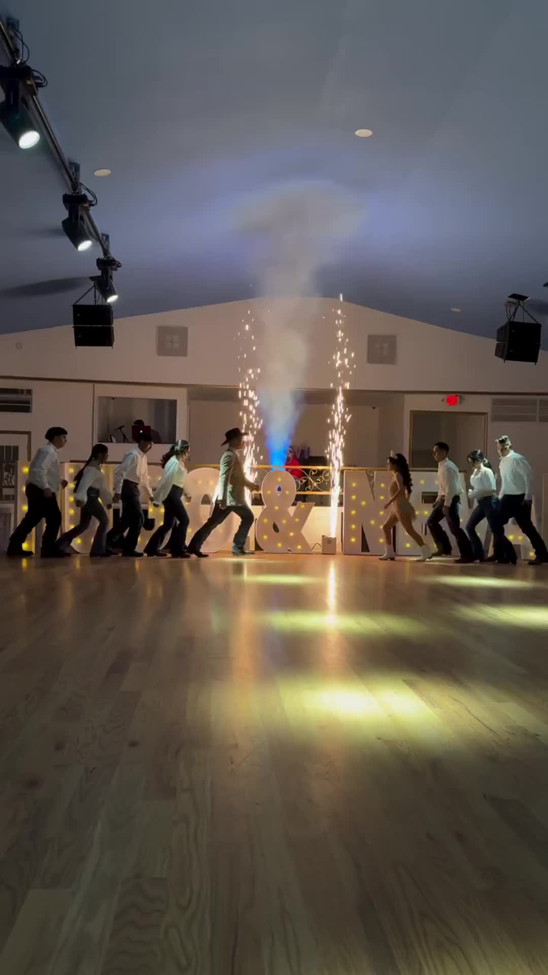 This may contain: a group of people dancing on a wooden floor in a dance studio with lights from the ceiling