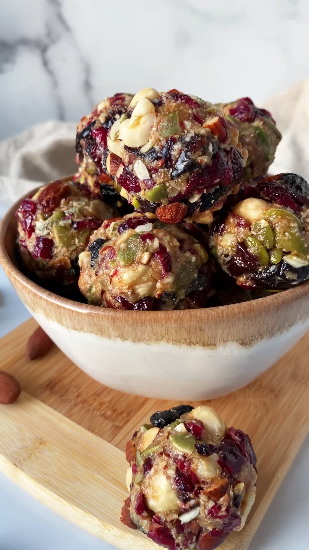 This may contain: a bowl filled with fruit and nuts on top of a wooden cutting board