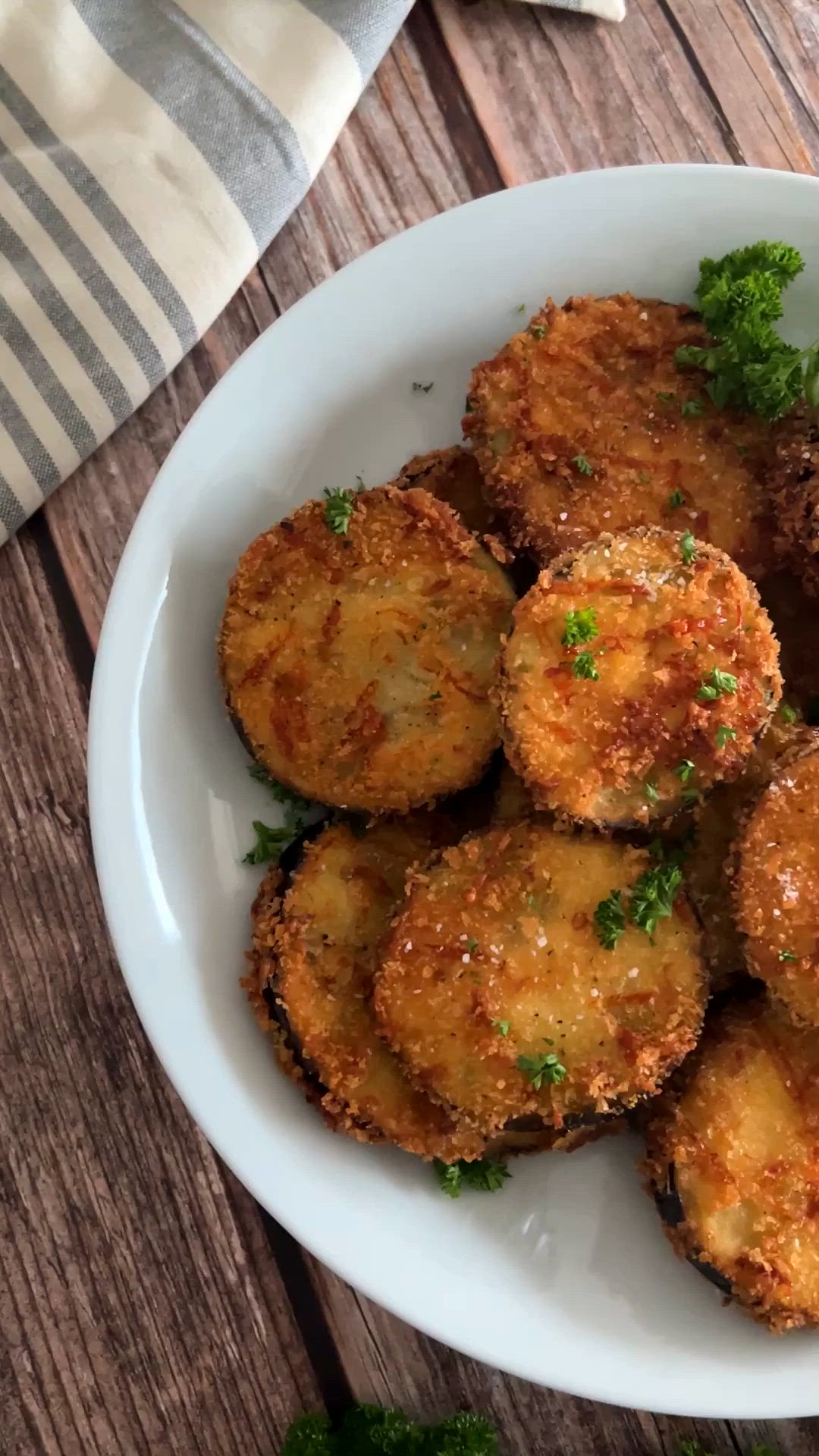 This may contain: a white bowl filled with fried food on top of a wooden table next to a napkin