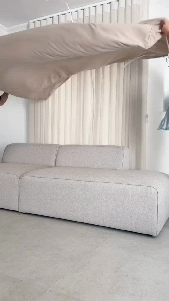 This may contain: a beige couch sitting in front of a window