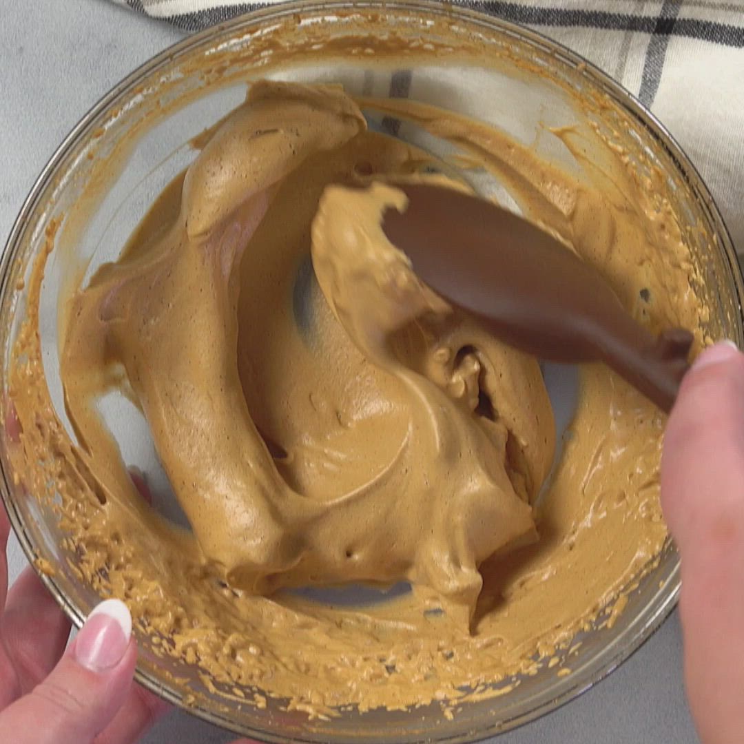 This may contain: someone is mixing peanut butter in a glass bowl